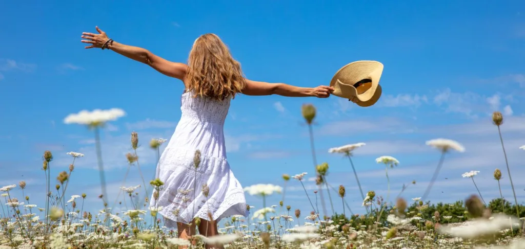 Woman dancing in a field with flowers on gratitude vacation